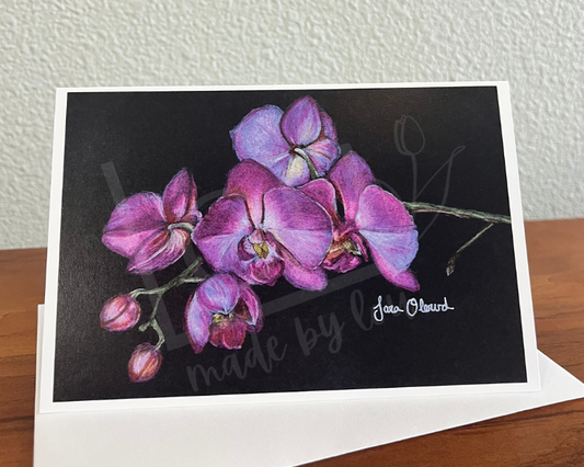 Greeting card with purple orchid design on a wooden surface