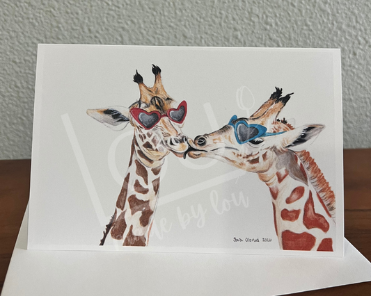 Card with illustration of two giraffes kissing on a wooden surface and gray wall background