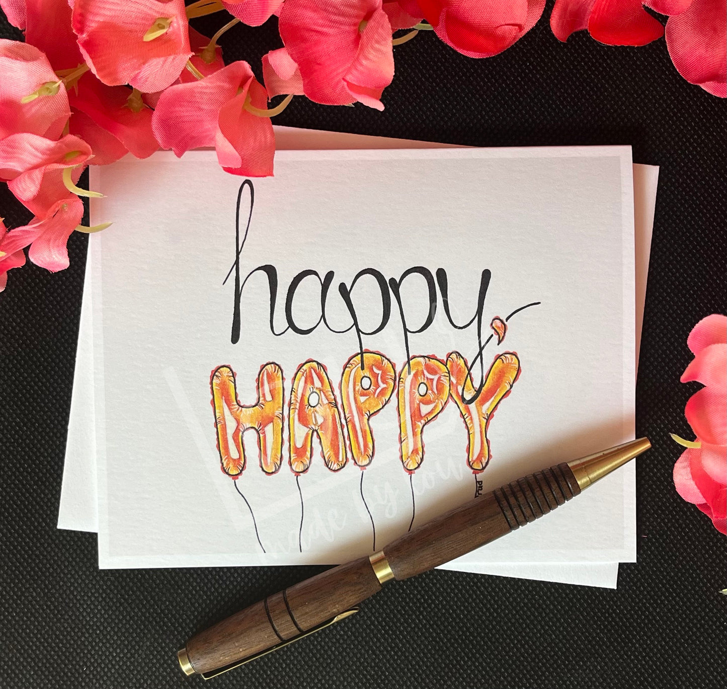 Card with 'happy happy' text, pen, and pink flowers on a black textured background