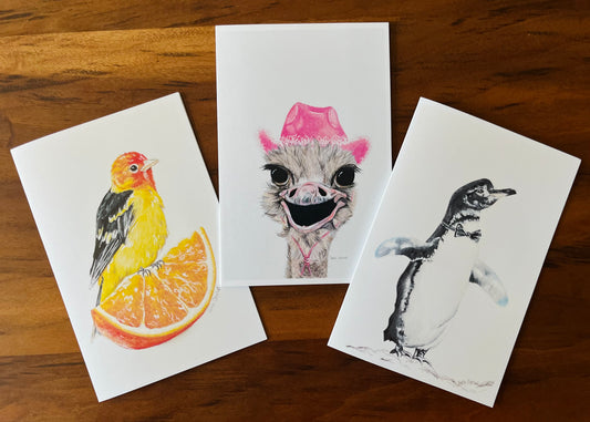 Three illustrated greeting cards on a wooden surface