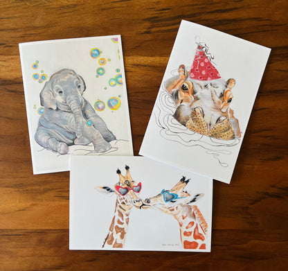 Three illustrated greeting cards featuring animals on a wooden surface.