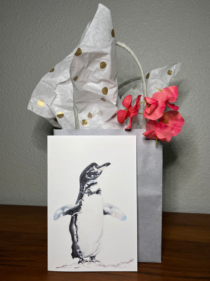 Penguin greeting card in front of a grey gift bag with polka dot tissue paper