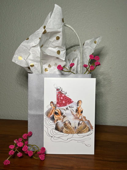 Gift bag with a card featuring dogs in Santa hats on a wooden surface.
