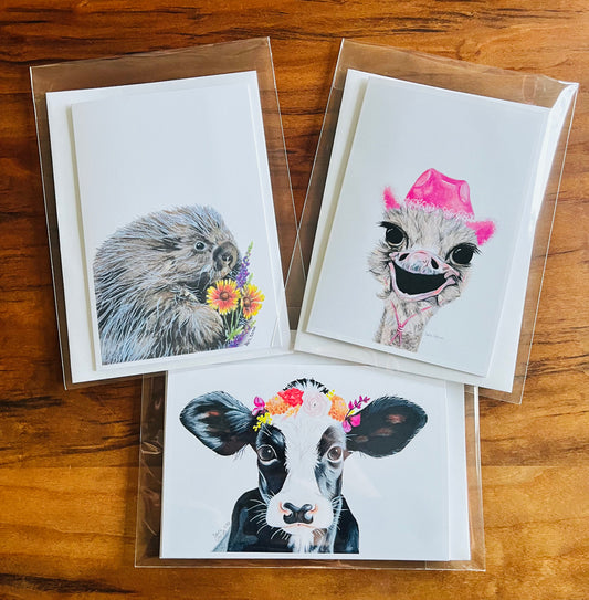 Three greeting cards with animal illustrations on a wooden surface